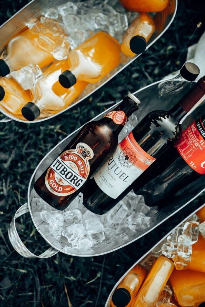 Photo by Burak Evlivan Overhead view of bottles of beer and juice chilling in ice buckets. Perfect for outdoor summer gatherings.