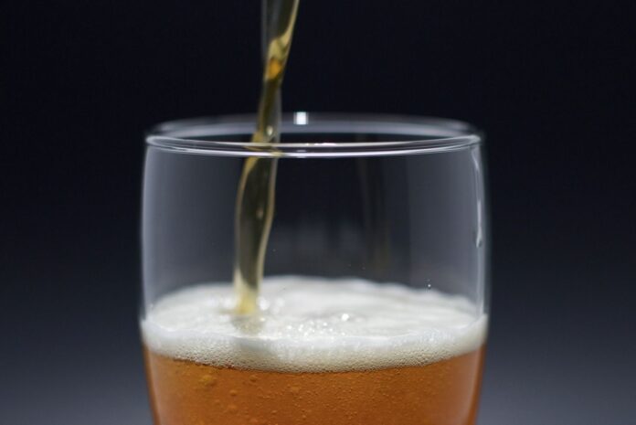 Photo by Andrew Patrick Photo A refreshing beer pouring into a glass, capturing the foam and texture in detail.